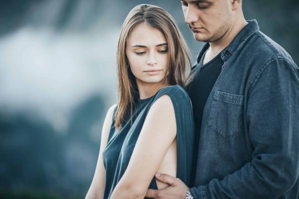 conflicted woman thinking about man as he hugs her