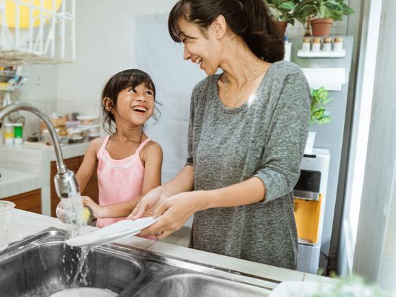 calm parent cleaning dishes with daughter